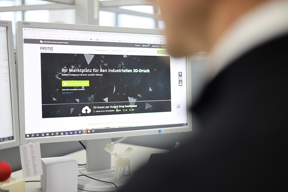 A person looking at a screen, where protiq.com is shown.